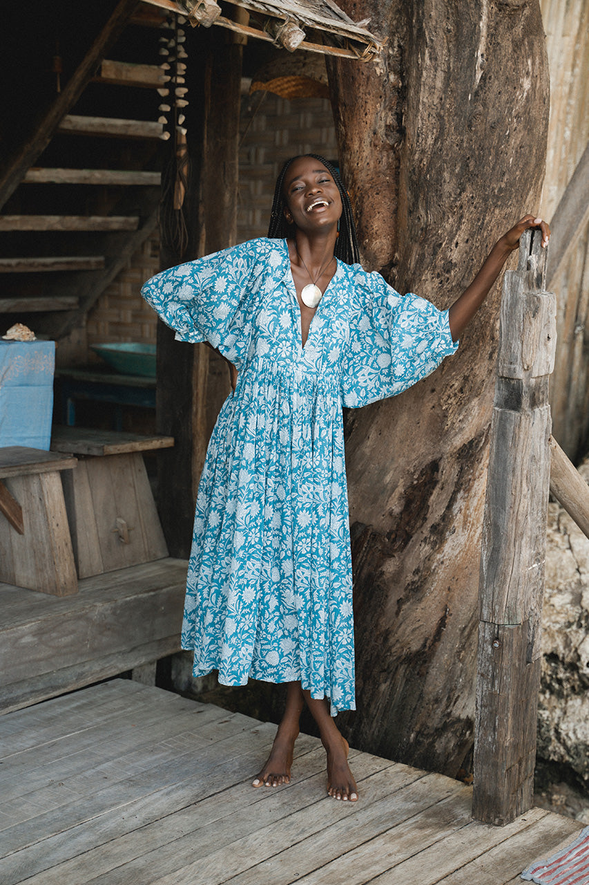 Daughters of India Kyra Midi Dress in Ocean Blue — smiling on wooden deck of tropical treehouse, billowed sleeves
